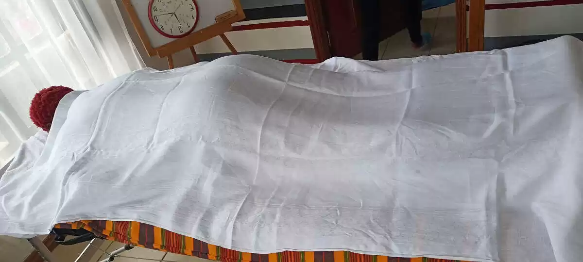 A client covered with a white sheet laying relaxed on massage table ready for massage treatment