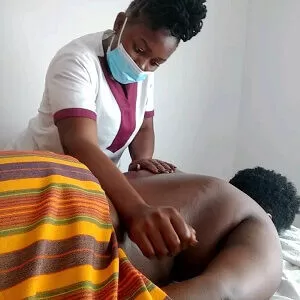 Massage therapist stroking the back muscles of a client with her forearm during a full-body massage treatment at the client's home in Nairobi