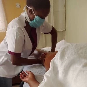 A massage therapist applies deep pressure on the thigh of a client with the palms of her hands