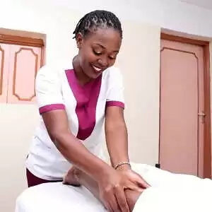 Massage therapist gently stroking the quad muscle of a client during a full-body massage treatment at the client's home in Nairobi