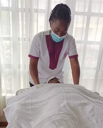 A massage therapist gently pressing on the shoulders of a client laying on her back on a massage table